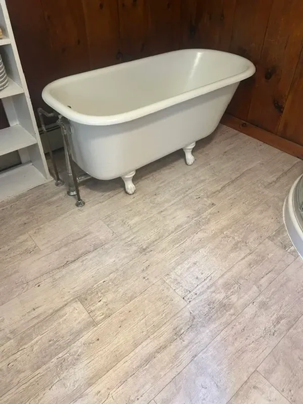 Clawfoot tub refinished with a bright white finish in a wood-paneled bathroom