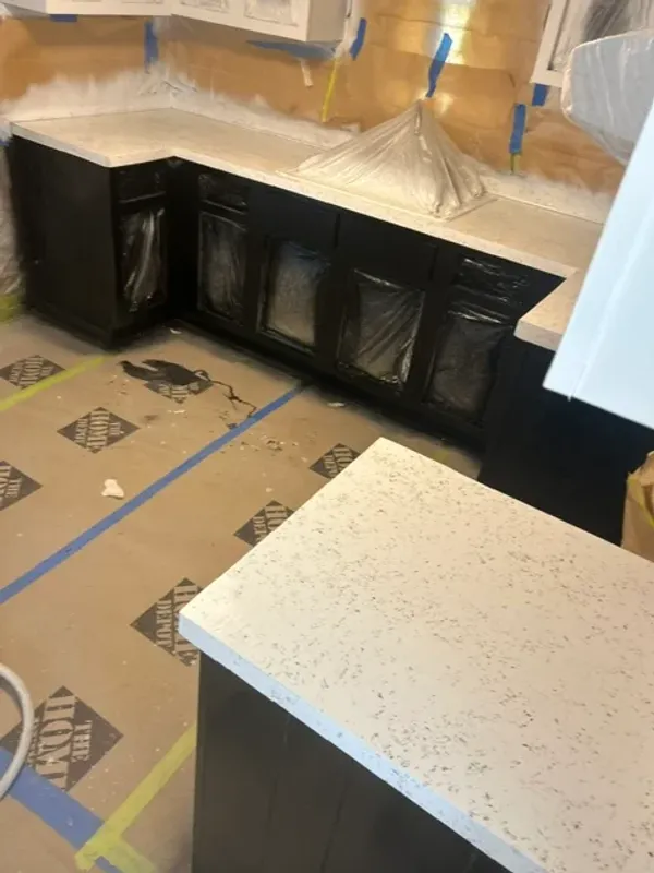 Resurfaced speckled white kitchen countertops curing, with surrounding cabinets and floor protected