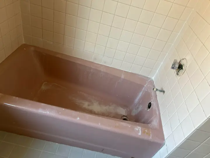 Worn pink bathtub and tile surround before reglazing